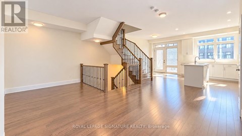A spacious room with wooden floors and a staircase leading to the upper level.