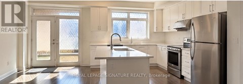 A kitchen with white cabinets and a stainless steel refrigerator.