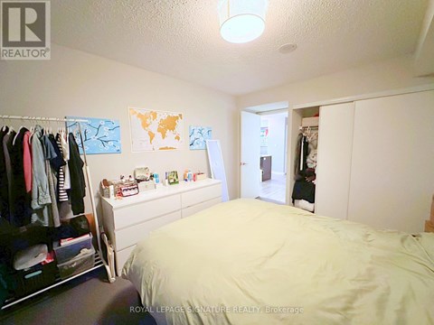 A bedroom with a bed, a wardrobe, and a dresser.