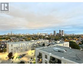A cityscape with buildings and a cloudy sky.
