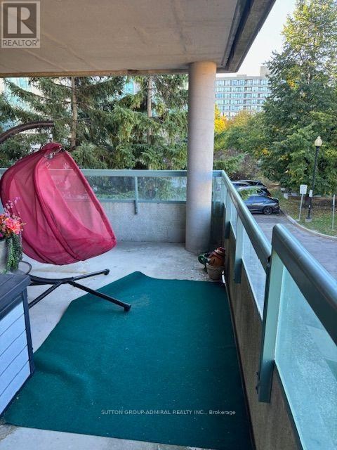 A red chair is on a balcony with a green mat.