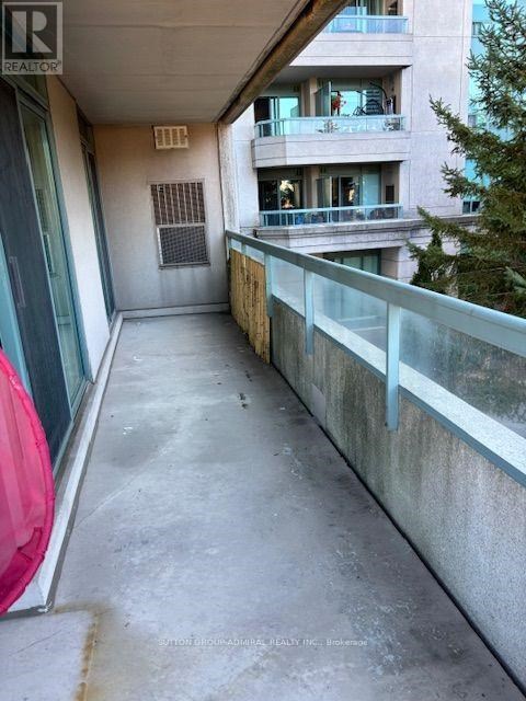 A balcony with a glass railing and a building in the background.
