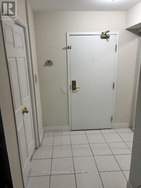 A white door with a gold handle is in a white room.