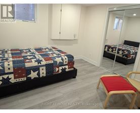 A bedroom with a bed covered in a quilt and a red chair.
