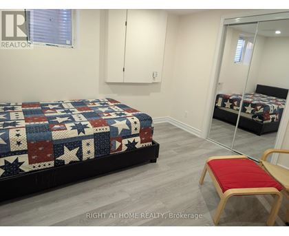 A bedroom with a bed covered in a quilt and a red chair.
