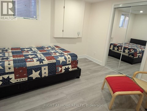A bedroom with a bed covered in a quilt and a red chair.