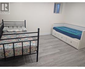 A bedroom with a black metal bed frame and a white bed with a blue mattress.