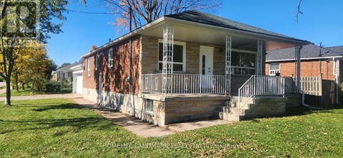 A small house with a porch and a tree in front.