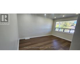 A room with a window and wooden flooring is for sale.