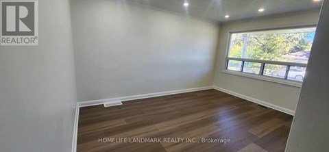 A room with a window and wooden flooring is for sale.