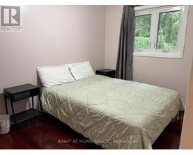 A bedroom with a bed, nightstand, and window.
