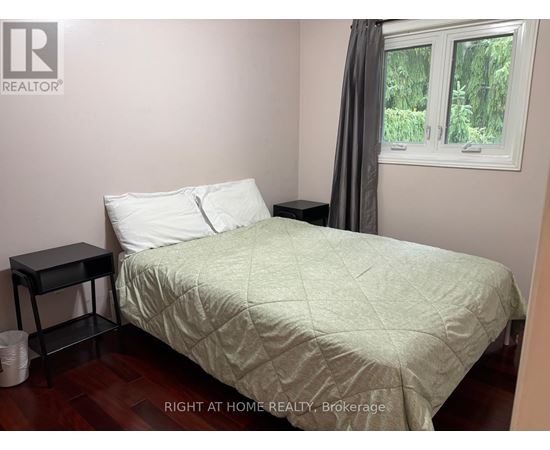 A bedroom with a bed, nightstand, and window.