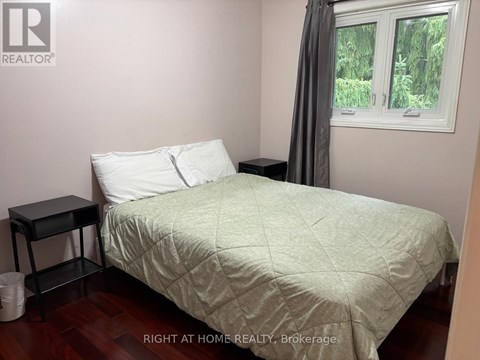 A bedroom with a bed, nightstand, and window.