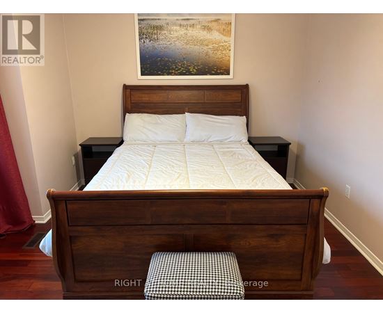 A bedroom with a bed, nightstand, and a painting on the wall.
