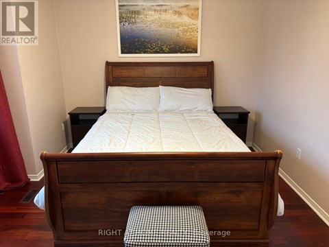 A bedroom with a bed, nightstand, and a painting on the wall.