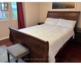 A bedroom with a large bed and a small stool.