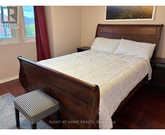 A bedroom with a large bed and a small stool.