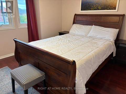 A bedroom with a large bed and a small stool.