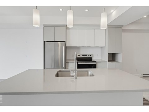 A modern kitchen with a stainless steel refrigerator and a double sink.