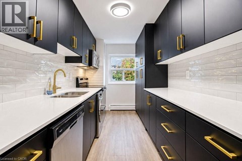 A modern kitchen with black cabinets and gold handles.