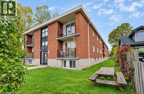 A red brick building with a balcony and a picnic table in front.