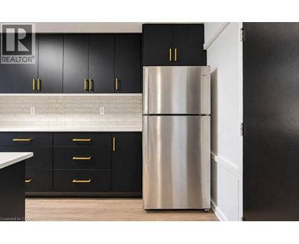 A stainless steel refrigerator in a kitchen with black cabinets.