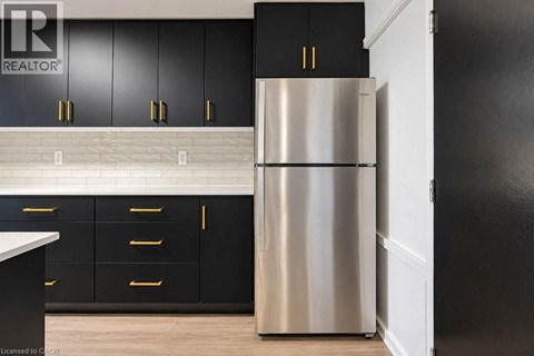 A stainless steel refrigerator in a kitchen with black cabinets.