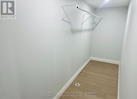A white wall with a light fixture and a wooden floor.
