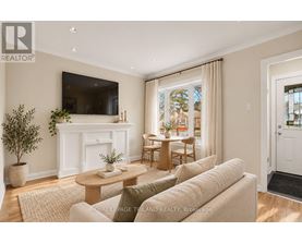 A living room with a white fireplace, a flat screen TV mounted on the wall, and a large window with curtains.