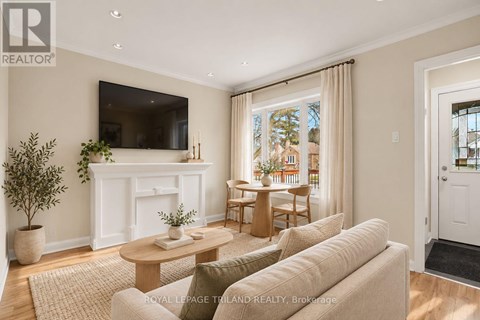 A living room with a white fireplace, a flat screen TV mounted on the wall, and a large window with curtains.
