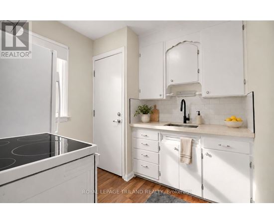A white kitchen with a black stove top and white cabinets.