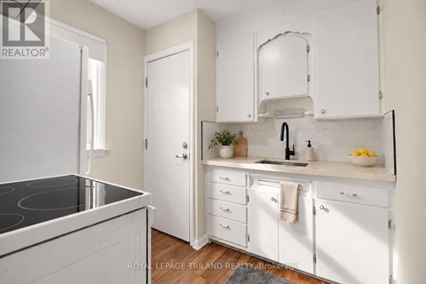 A white kitchen with a black stove top and white cabinets.