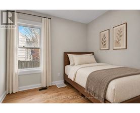 A bedroom with a bed, two pictures on the wall, and a window with curtains.