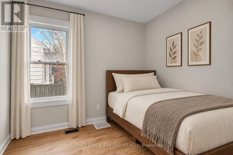 A bedroom with a bed, two pictures on the wall, and a window with curtains.