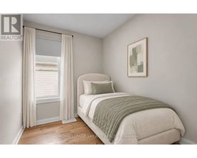 A bedroom with a bed, pillow, and a window with curtains.