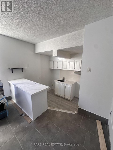 A kitchen under construction with a white cabinet and a white box on the floor.