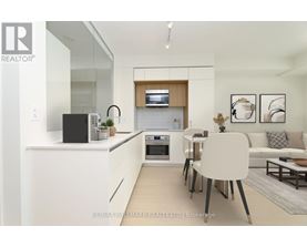 A modern kitchen with white cabinets and a black speaker on the counter.