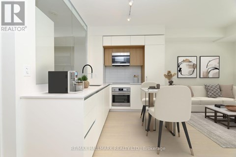 A modern kitchen with white cabinets and a black speaker on the counter.