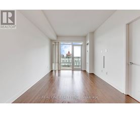 A spacious room with wooden floors and a view of a cityscape through the windows.