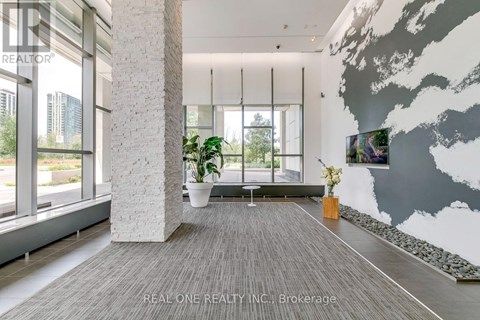 A modern living room with a grey carpet and a large grey and white mural on the wall.