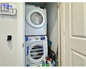 A white washing machine is in a small space between a door and a wall.