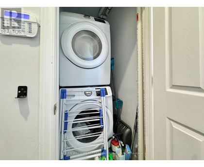 A white washing machine is in a small space between a door and a wall.