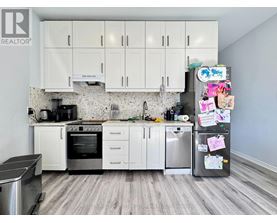 A kitchen with white cabinets and a fridge covered in magnets.