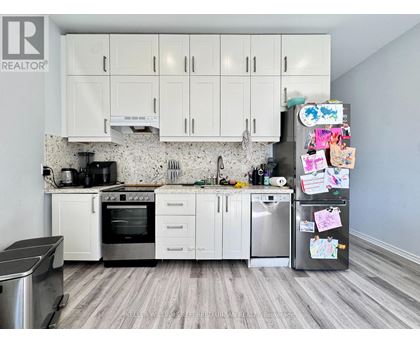 A kitchen with white cabinets and a fridge covered in magnets.