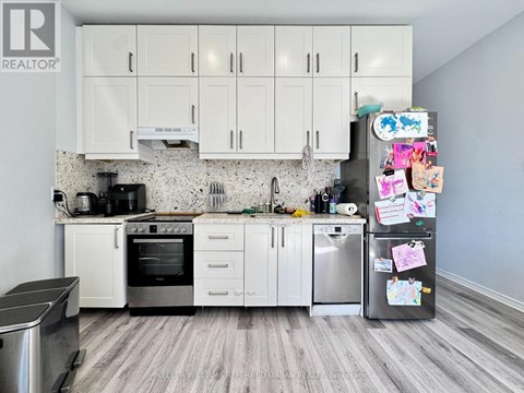 A kitchen with white cabinets and a fridge covered in magnets.