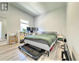 A bedroom with a bed, a desk, and a window.
