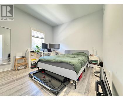 A bedroom with a bed, a desk, and a window.