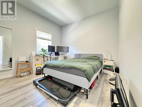 A bedroom with a bed, a desk, and a window.