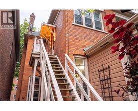 A red brick house with a white staircase leading to the second floor.