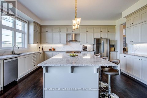 A kitchen with white cabinets and a marble island.
